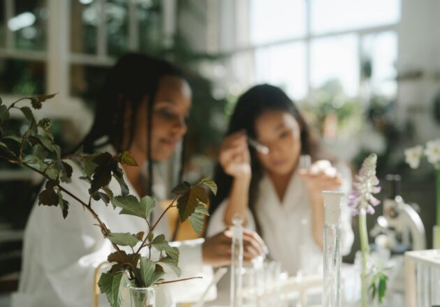 Two female scientists work in a lab filled with greenery.