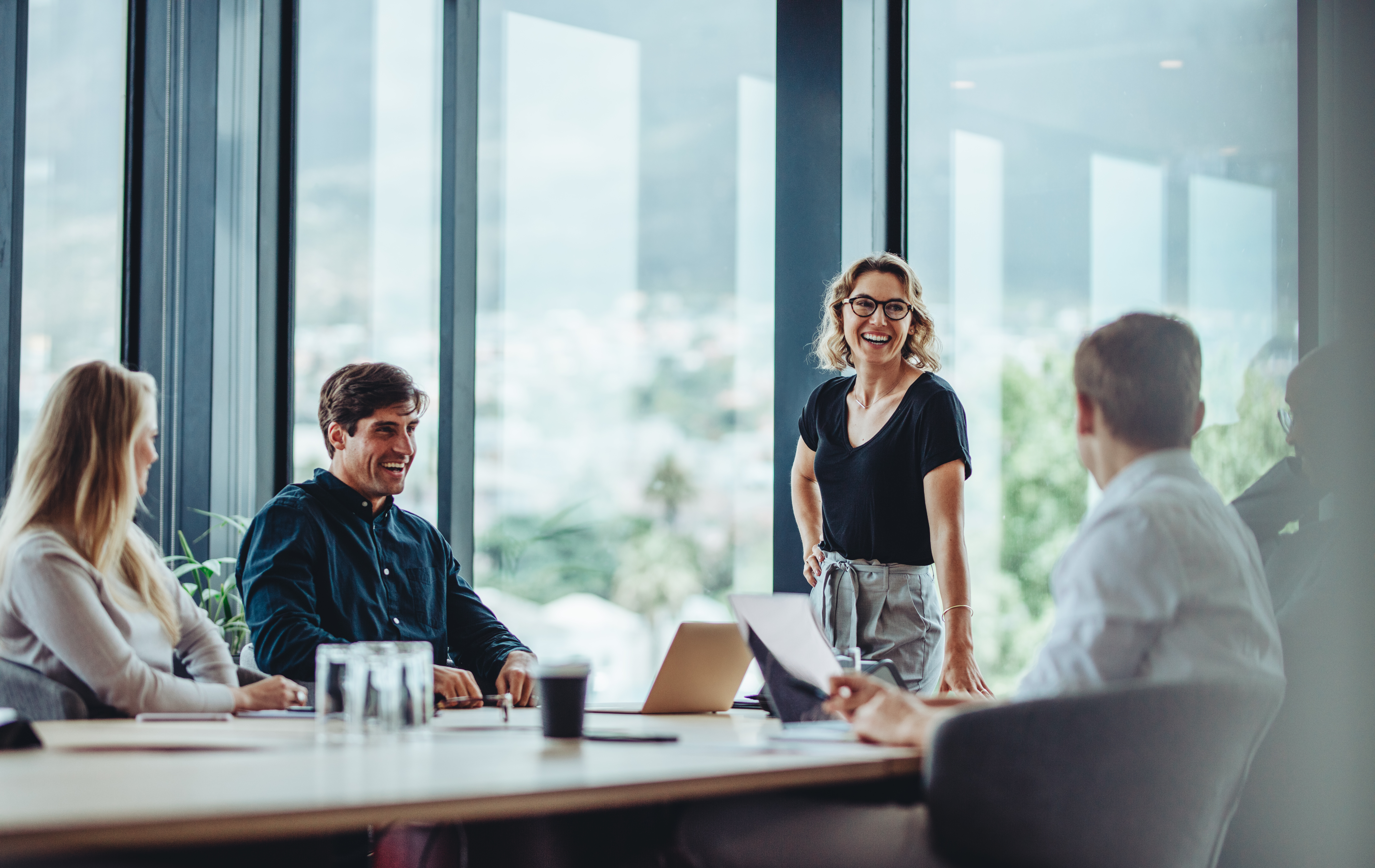 Coworkers laugh together while sitting around a table during a meeting.