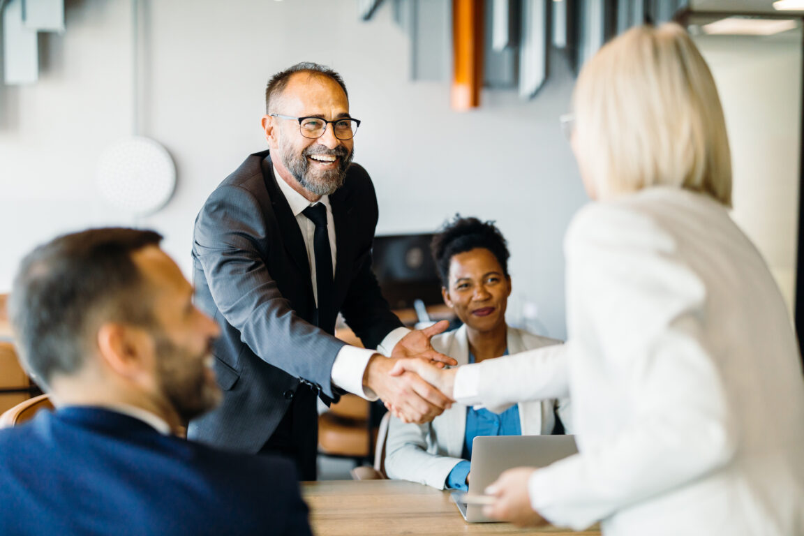 Smiling business professionals celebrating a successful negotiation with a handshake, emphasizing positivity and accomplishment in the workplace